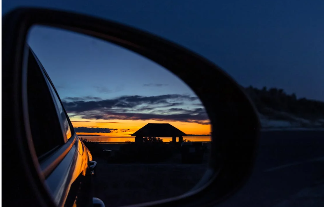 A pavillion at sunset reflected in a vehicle side mirror